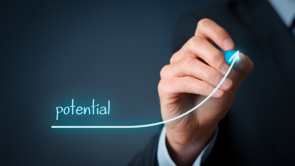 A person in a suit drawing an ascending arrow above the word 'potential,' symbolizing growth or success.