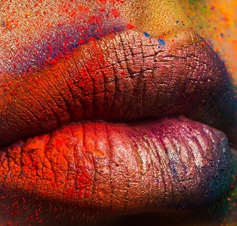 Close-up of colorful powdered lips in vibrant red and orange tones.