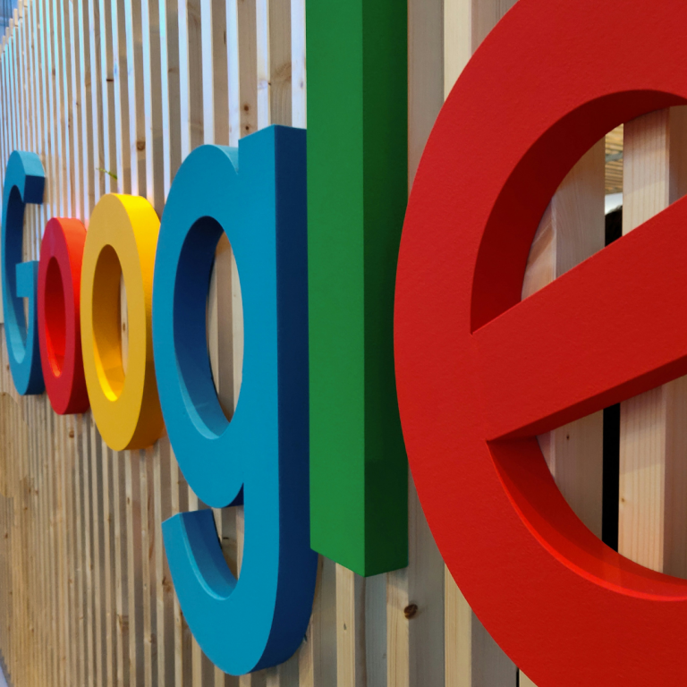 Colorful Google logo displayed in a three-dimensional design on a wooden slat background.